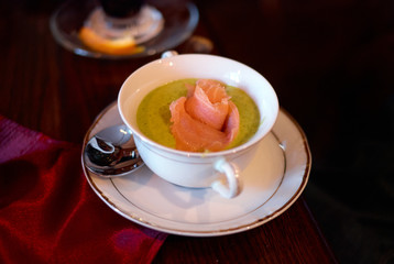 Cream soup with broccoli and salmon on wooden table