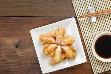 fried crab sticks in a ceramic plate served with soy sauce on wooden table, top view. delicious food appetizer.
