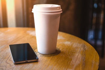 A smartphone rests on a table in a cafe, with a coffee glass