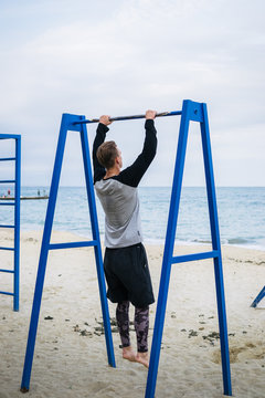 Young man doing parkour tricks on the beach near the sea