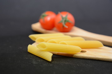 penne rigate pasta italiana con pomodori sullo sfondo