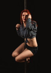 Fototapeta premium beautiful go-go dancer in denim shorts and checkered shirt in night club. Pole Dance pin-up girl