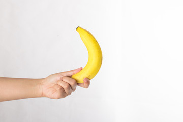 Hand holds a banana isolated on white background.