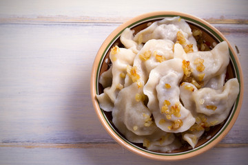 Pierogi or pyrohy, varenyky, vareniki, dumplings in bowl on wooden table. horizontal