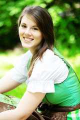 young woman in dirndl sitting on blanket in park