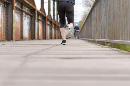 Sporty woman running on an old boardwalk bridge