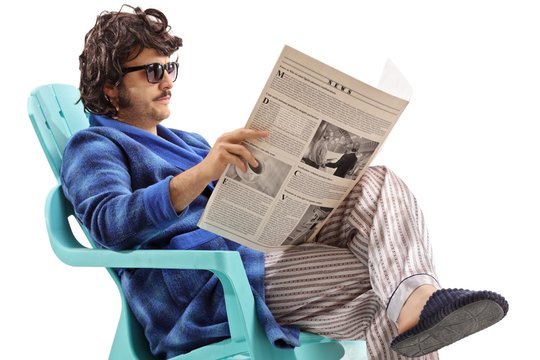 Young man sitting in a plastic chair and reading a newspaper