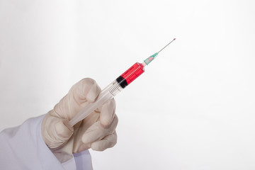 Doctor hand in a glove and holding syringe with liquid. Isolated on white background.