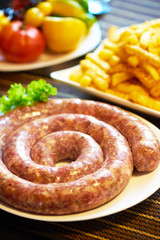 Grilled sausages with potatoes fries on blurred background, close-up.