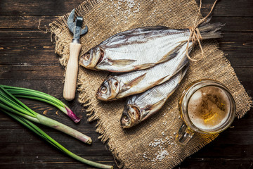 close-up dried fish, vintage glass of beer on a dark wooden background. Top view. Horizontal orientation.