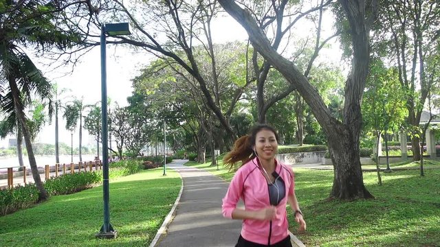 Slow motion - Young asian woman running on sidewalk in morning. Young sport asian woman running in the park. Fitness running sport people and healthy lifestyle concept.