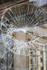 Hole in broken shattered security glass, insurance, security, vandalism or crime concept, shape of...