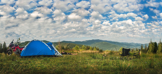 Camping under the sky at morning in mountains, motorcycle touring, dual sport enduro off road panorama, top of mountain, tent and off road adventure motorcycles, man doing morning exercises in nature