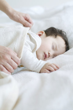 赤ちゃんに毛布をかける母親の手元