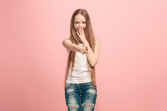 The happy teen girl pointing to you, half length closeup portrait on pink background.