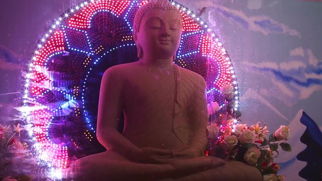 Buddha statue surrounded by flashing colorful festive lights on an abstract background in a Buddhist temple.