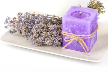 Still life with lavender candle and dry lavender on a white plate on white background