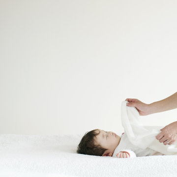赤ちゃんに毛布をかける母親の手元