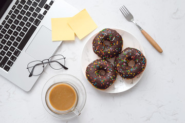 Food in the office. Donuts on working desk.