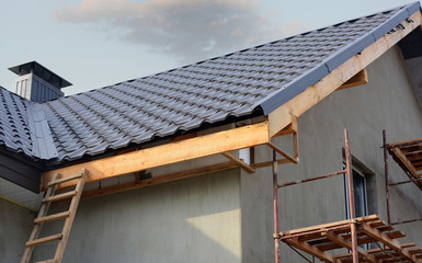 Metal roof construction with coaxial chimney pipe heating system against blue sky.
