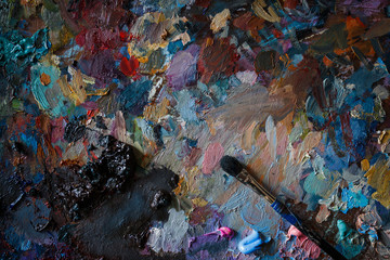 Artist's palette with multi-colored smeared colors and one brush. Close up.