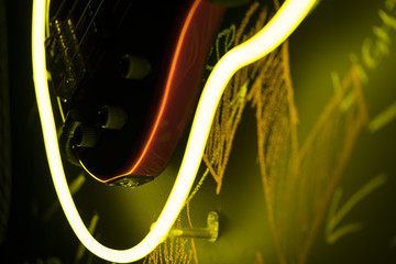 Abstract music wallpaper, closeup of bass guitar body surrounded by neon light