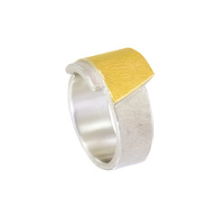Damenring aus Sterlingsilber. Auf eine breite Ringschiene ist ein Trapez aus Silber mit einer Belötung aus Gold zu sehen. Die Oberflächen sind geschmiergelt und poliert.