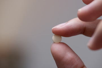 Finger holding a tablet of medicine