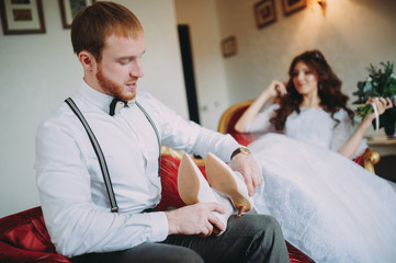 Obraz premium Bride and groom sitting at the bar on the couch. Cute married couple in cafe, groom kissing a bride. Pure tenderness