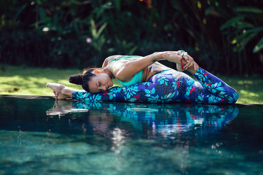 Woman practicing yoga at infinity pool