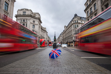 London, England - British umbrella at busy Regent Street with iconic red double-decker buses on the...