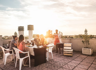 Trendy friends having barbecue party on top of the roof - Happy people doing bbq dinner outdoor  -...
