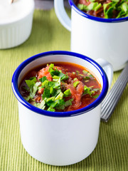 Russian beetroot soup borscht in enamel mugs on green cloth