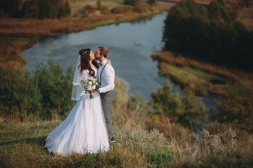 wedding. stylish groom with a beard and a beautiful bride on background of the river. rustic style. boho.