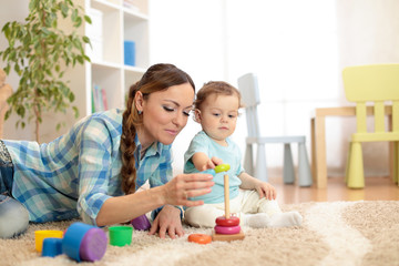 Baby boy and mother playing toy rings. Toddler kid plays pyramid, children early education