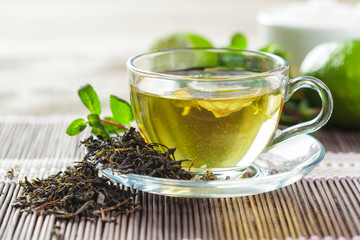 cup of black tea with mint leaves on a wooden table
