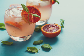 Blood orange cocktail with slices of orange on turquoise background. Toned