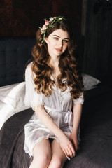 Morning of the bride. Beautiful portrait of a bride in a peignoir with hair curls and fresh flowers