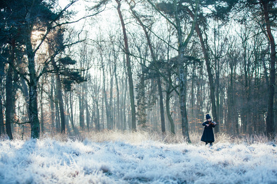 Little Girl playing violin in a snowy forest