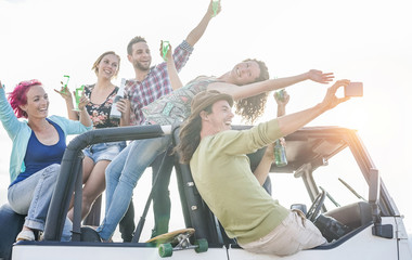 Happy friends taking selfie during party in desert on convertible off road car