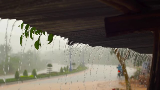 Slowmotion shot of a heavy rain and water faling from a roof of a building.