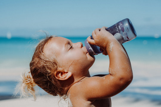 Kind trickt gen&uuml;sslich aus einer Flasche am Strand
