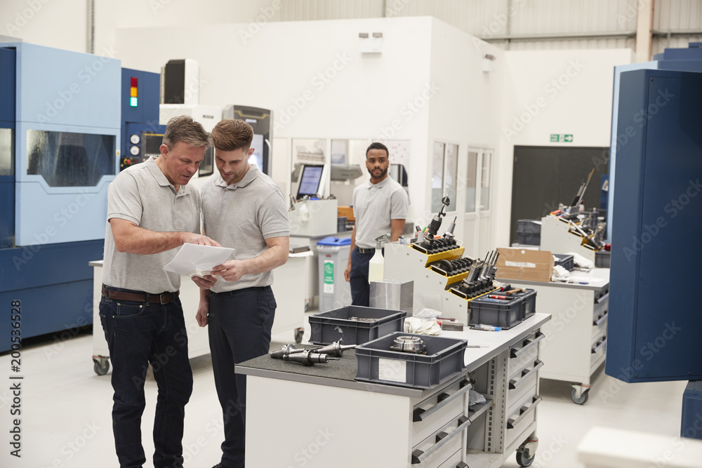 Wall mural engineer and apprentice meet on floor of engineering workshop