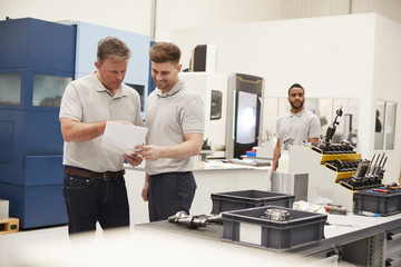 Obraz premium Engineer And Apprentice Meet On Floor Of Engineering Workshop