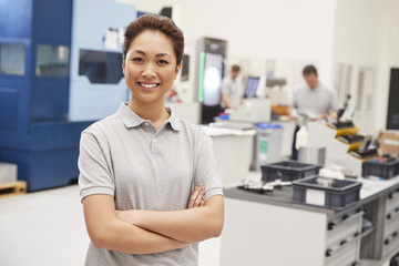 Portrait Of Female Engineer On Factory Floor Of Busy Workshop