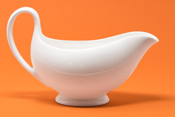 A white jug set against a bright orange background