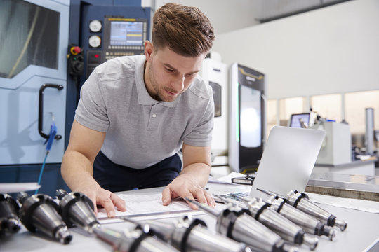 Male Engineer Measuring CAD Drawings In Factory