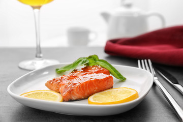Fish fillet served with lemon slices and fresh basil leaves on kitchen table