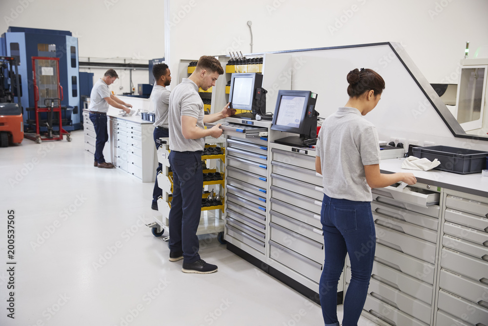 Wall mural engineers selecting tools for use on machinery in factory