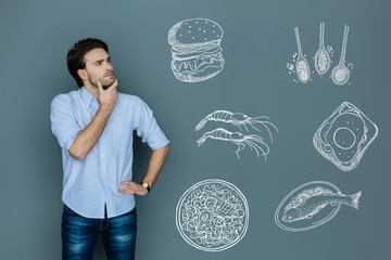 New restaurant. Calm professional talented chef touching his chin while thinking about his wonderful unique restaurant